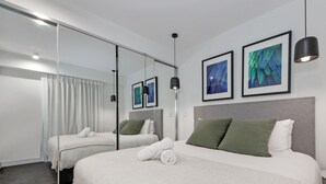 Ein modernes Hotelzimmer mit einem großen Bett, zwei Nachttischen, einem Spiegel und Kunstwerken an den Wänden.