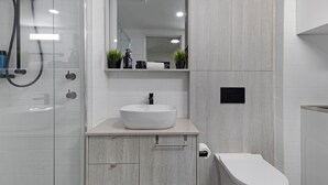 Ein modernes Badezimmer mit einem weißen Waschbecken, einer Toilette und einer Duschkabine.
