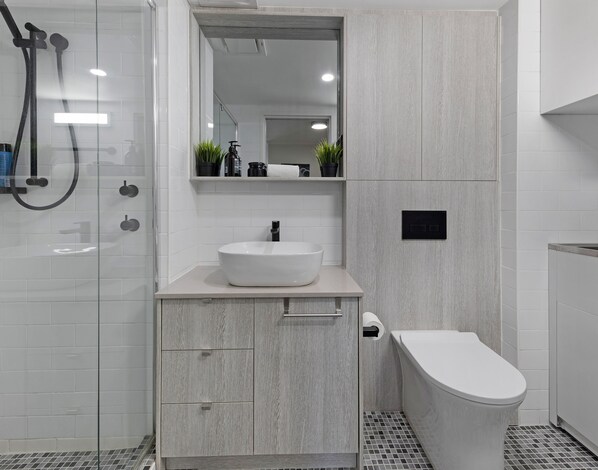 Een moderne badkamer met een wit wastafelmeubel, toilet en douche.
