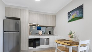 Eine moderne Küche mit Edelstahl-Kühlschrank, Einbauofen und Geschirrspüler. Ein Esstisch mit Blumenvase und einem Bild an der Wand.