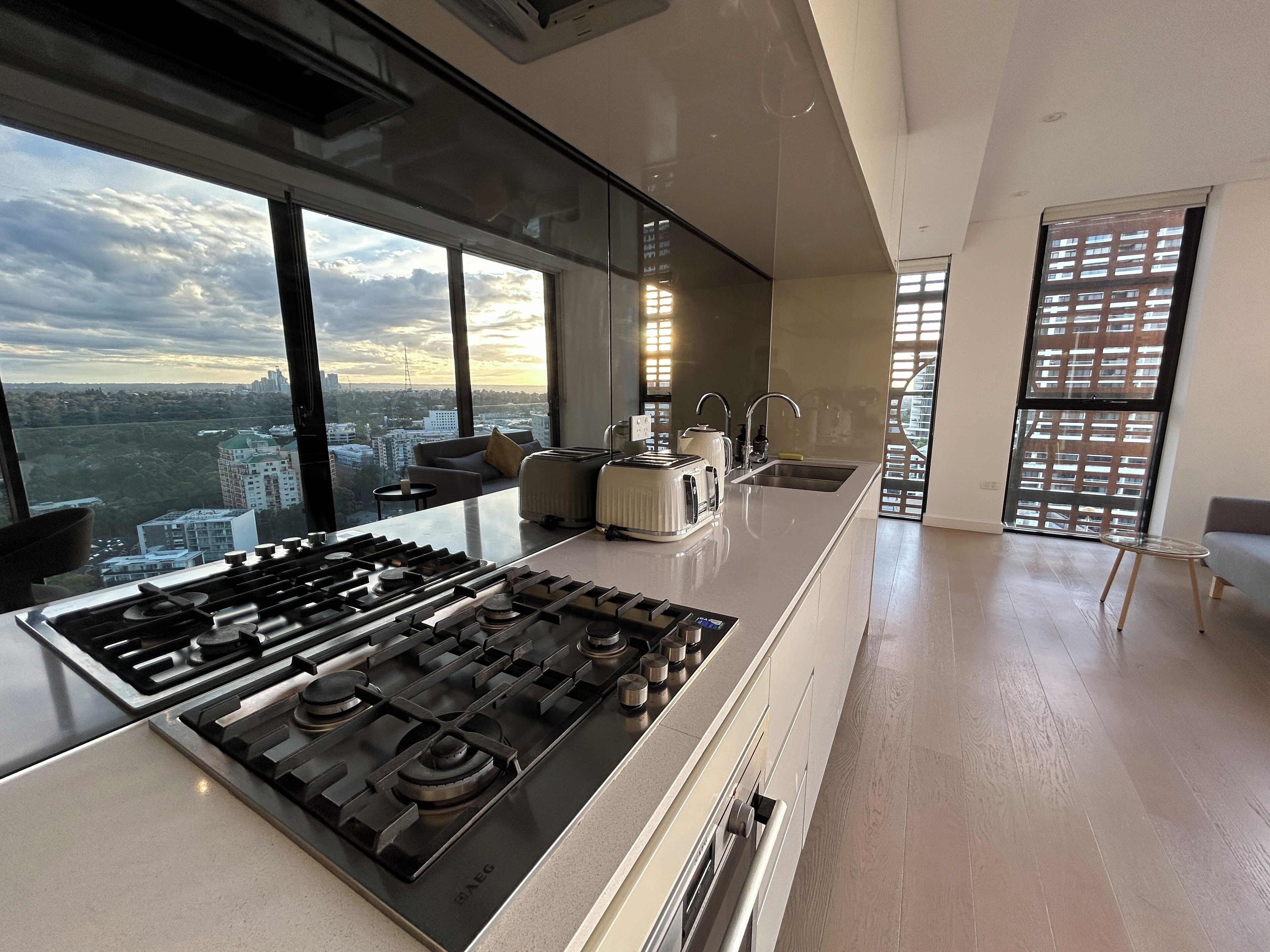 Una cocina moderna con una estufa a gas grande, un fregadero y vistas de la ciudad a través de amplios ventanales.