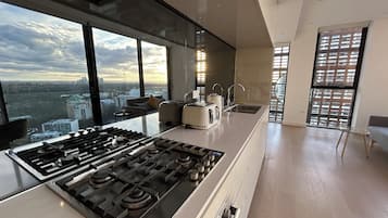 Una cocina moderna con una estufa a gas grande, un fregadero y vistas de la ciudad a través de amplios ventanales.