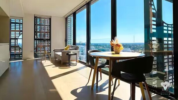 A modern living room with a large window offering a city view, a round table, and a sofa. - Kozyguru |St Leonards | 1 Bed Best Location & View (St Leonards)