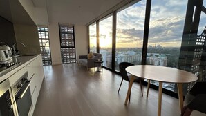 A modern apartment with a kitchen, dining area, and large windows offering a city view. - Kozyguru |St Leonards | 1 Bed Best Location & View (St Leonards)