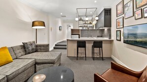 Uma sala de estar moderna com um sofá seccional, uma mesa de centro redonda e um espaço de bar com banquetas.