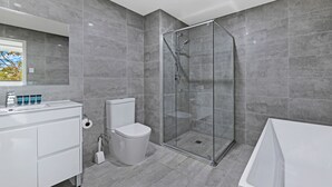 Un baño moderno con ducha de vidrio, lavamanos blanco y una bañera grande.