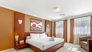 A hotel room with a large bed, a nightstand, a chair, and a window with curtains. - Kozyguru | Westleigh | 4 Bed Room | Free Parking (Westleigh)