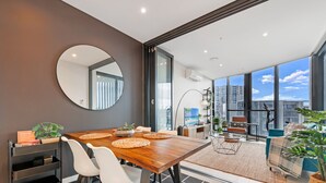 A modern dining area with a wooden table, white chairs, and a large mirror.