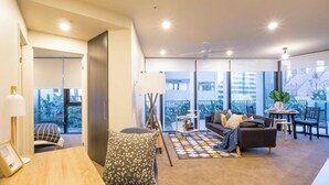Una sala moderna con sofá, mesa de centro y vista a la ciudad a través de amplias ventanas.