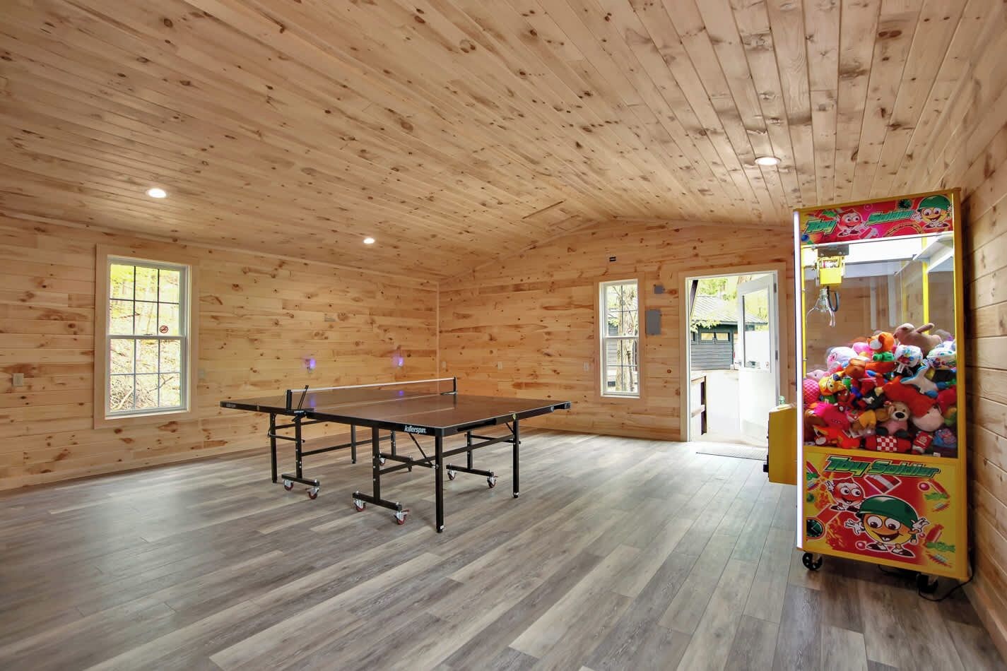 Ein Zimmer mit Tischtennisplatte, Holzwänden und einer Krabscheibe.