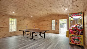 A room with a ping pong table, wooden walls, and a claw machine.