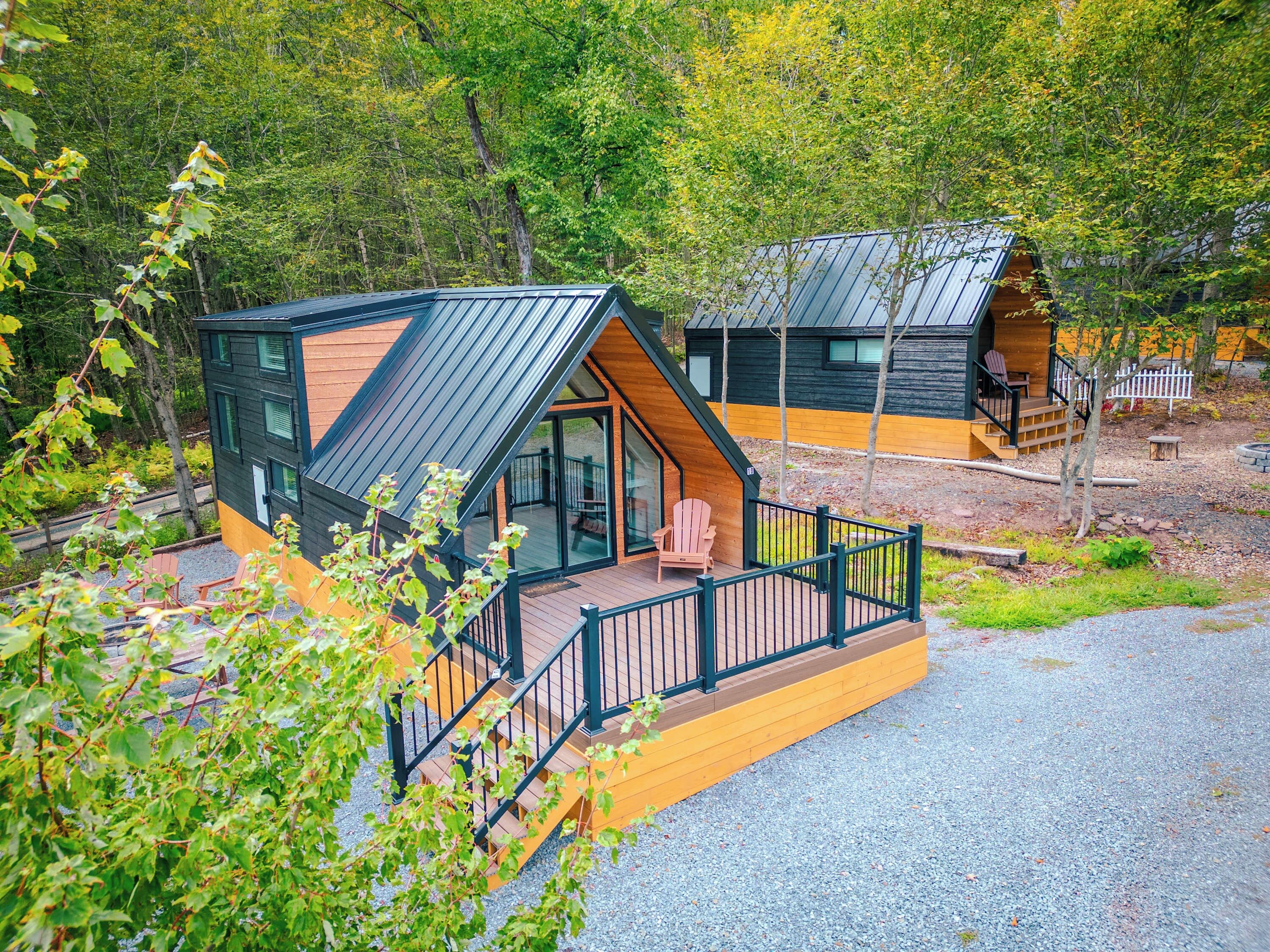 A cabin with a deck, a glass door entrance, and a small porch with chairs.