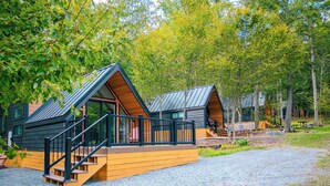 A cabin with a wooden deck and a staircase leading to the entrance. - Cedar Nook (Wellsboro)