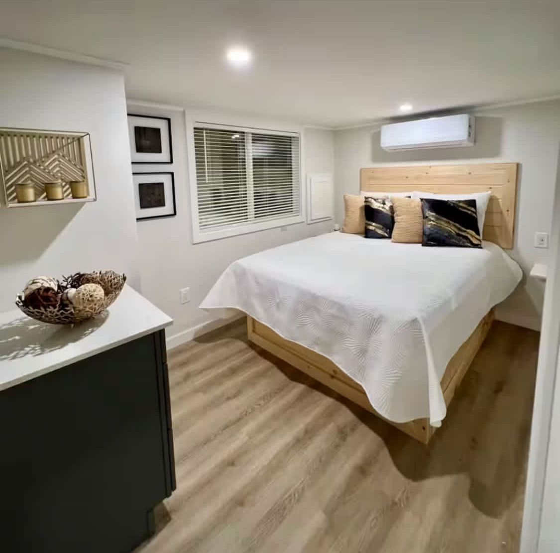 A bedroom with a bed, bedside table, and a decorative wall piece.