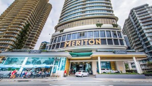A hotel with a curved facade, multiple balconies, and a prominent 'Meriton' sign.