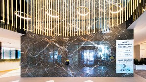 A modern lobby with a marble wall, a sales center, and a sign for luxury apartments.