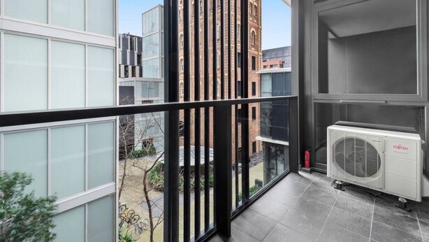 A modern apartment with large windows, a view of a historic building, and a Fujitsu air conditioning unit.
