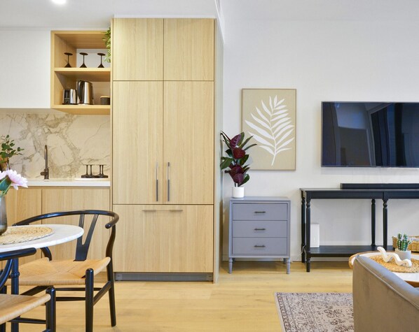 Una cocina moderna con armarios de madera, salpicadero de mármol y un comedor con una mesa redonda y sillas.