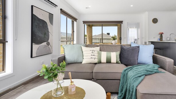 Ein modernes Wohnzimmer mit einem grauen Ecksofa, einem runden Couchtisch und Blick ins Freie.