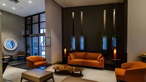Un vestíbulo moderno con un sofá, dos sillones, una mesita de centro y un ventanal grande.