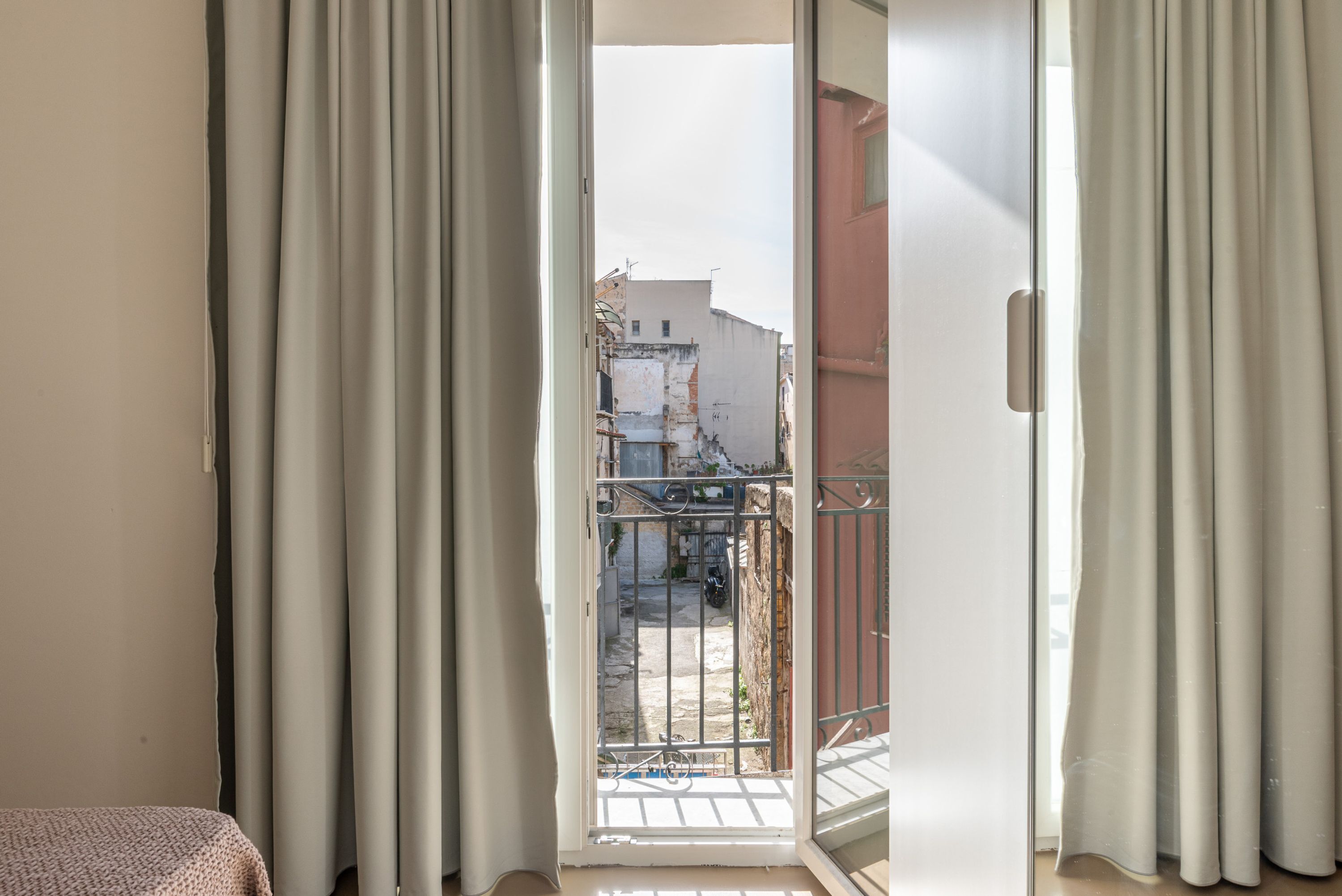 Ein Zimmer mit einer Schiebetür aus Glas, die auf einen Balkon mit Metallgeländer führt.