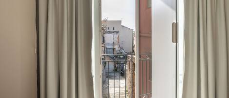 Ein Zimmer mit einer Schiebetür aus Glas, die auf einen Balkon mit Metallgeländer führt.