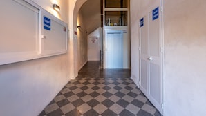 Un couloir doté d’un sol à carreaux, de murs blancs et de portes portant l’inscription « LOCALE AUTOLABE ».