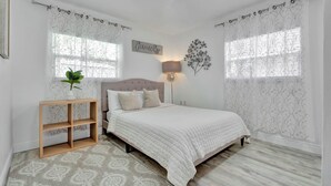 A bedroom with a bed, a bedside table with a plant, a wall-mounted lamp, and a decorative wall piece. - Charming 2-bedroom apartment in lovely DeBary with AC, WiFi (DeBary)