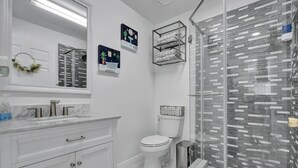 A modern bathroom with a white vanity, a toilet, and a glass shower enclosure. - Charming 2-bedroom apartment in lovely DeBary with AC, WiFi (DeBary)