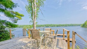 Une terrasse en bois, agréée de mobilier d’extérieur, donnant sur un lac.