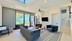 A modern living room with a sofa, armchairs, a coffee table, and a TV.