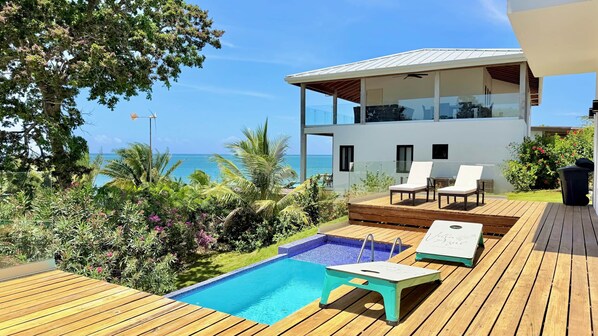 Une villa moderne dotée d’une piscine, de chaises longues et offrant une vue sur l’océan.