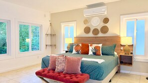 A bedroom with a bed, bedside lamps, a hanging light, and a window.
