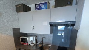 A compact kitchen with stainless steel appliances, including a microwave, coffee maker, and dishwasher.