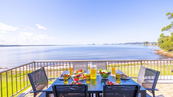 Une table dressée sur une terrasse, offrant une vue sur un lac paisible et des collines lointaines.