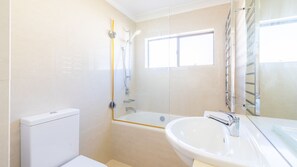 Une salle de bain moderne équipée de toilettes, d’une douche à parois de verre et d’un lavabo.