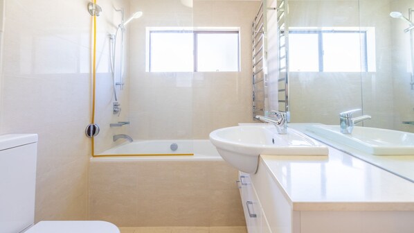 Une salle de bain moderne avec une baignoire, un lavabo et un miroir.