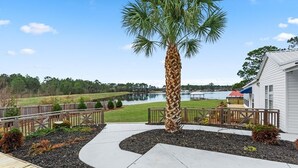 A well-maintained outdoor area with a palm tree, a wooden deck, and a view of a lake. - The Charming Villa C, located by the pool, is an ideal getaway. (Moultrie)
