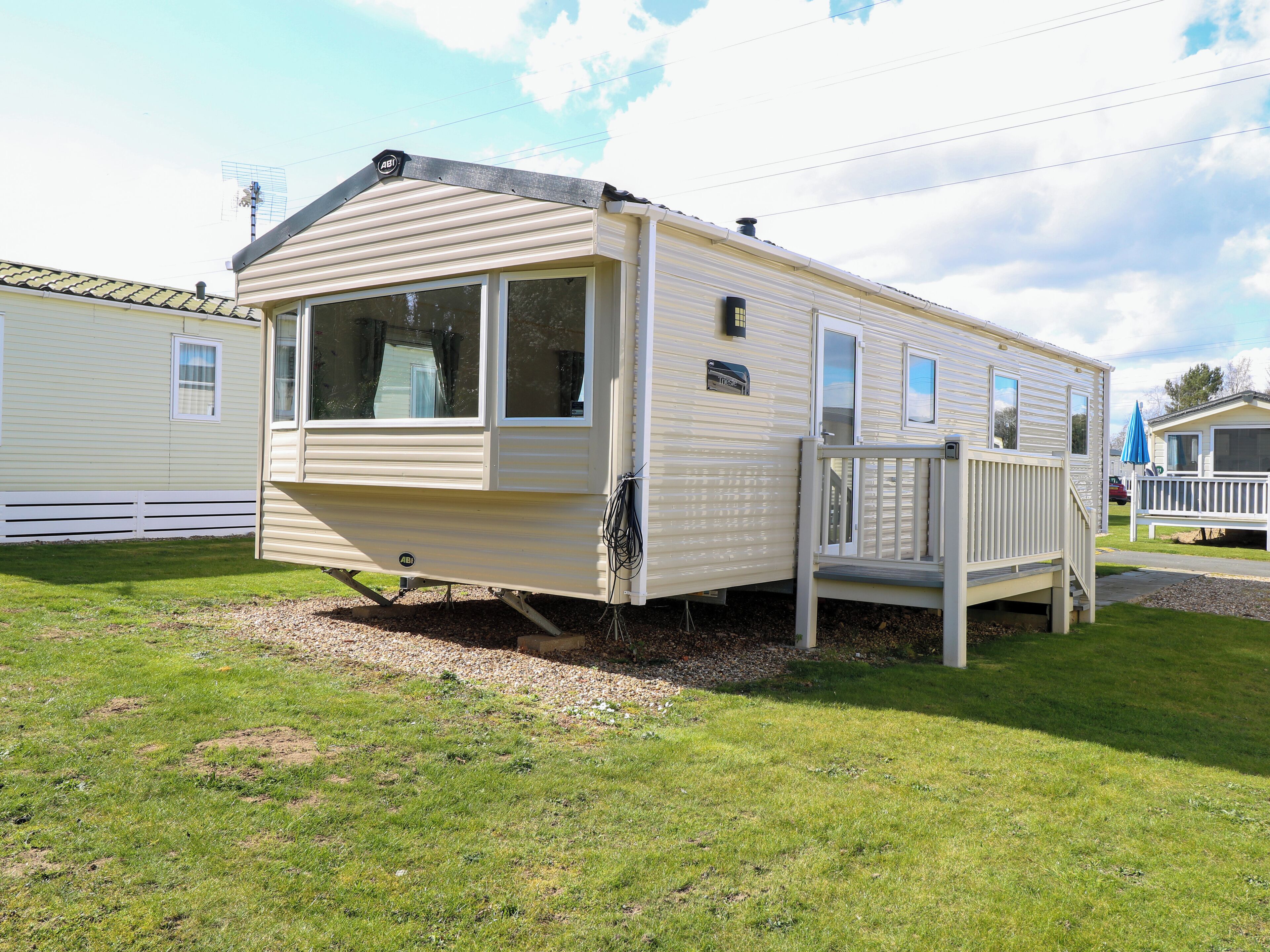 A mobile home with a front porch, a mailbox, and a small deck.