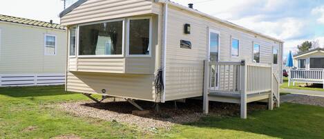 A mobile home with a front porch, a mailbox, and a small deck.