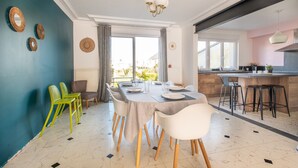 A dining area with a table set for six, surrounded by chairs, and a kitchen area with stools.