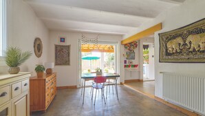 A spacious room with a dining area, a wooden cabinet, and a radiator. - Jardin Bohème - Jardin, terrasse et cuisine d'été. (Marseille)