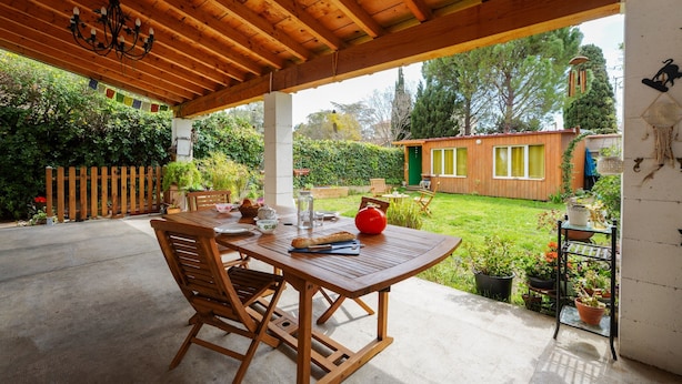 A wooden patio with a table and chairs, surrounded by potted plants and a wooden fence. - Jardin Bohème - Jardin, terrasse et cuisine d'été. (Marseille)
