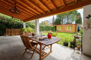 Eine Holzterrasse mit Tisch und Stühlen, umgeben von Topfpflanzen und einem Holzzaun.