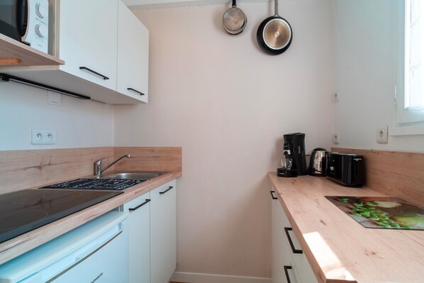 Una cocina moderna con armarios blancos, encimera de madera, estufa integrada, un lavabo y una cafetera.
