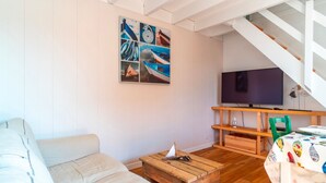 Una sala de estar con un sofá, una mesa de centro de madera, un televisor y una escalera.