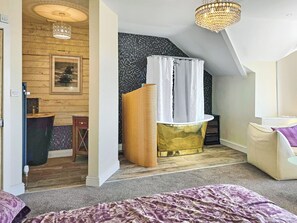 A bedroom with a bed, a shower area, and a wooden floor. - 4 bedroom accommodation in St Bees (St Bees)