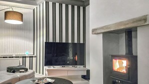 Un salon moderne doté d’un téléviseur à écran plat, d’une cheminée et d’une table basse ronde.