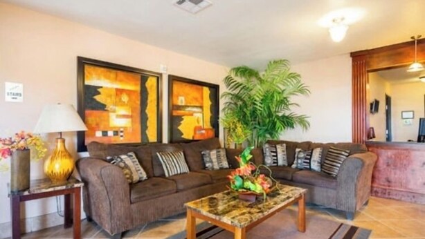 A living room with a sofa, a coffee table, a lamp, and a plant. - Franklin Inn & Suites (Franklin)