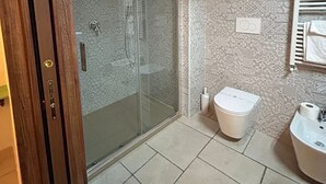Un baño con cabina de ducha de vidrio, inodoro y lavamanos.